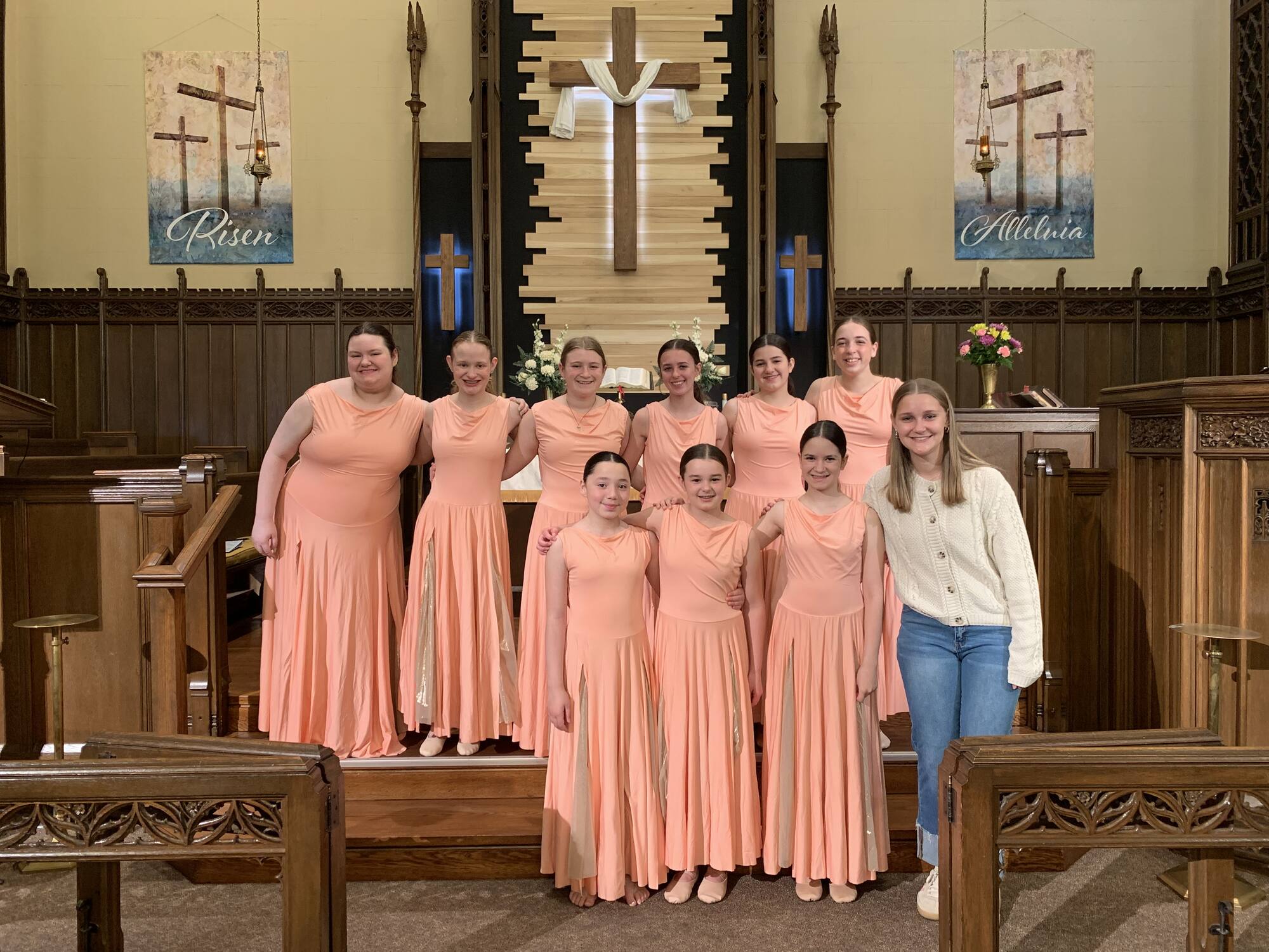 Worship dance team in peach dresses with their teacher at a church altar